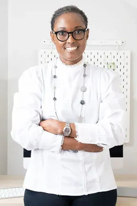 Studio portrait of Dr. Égo Obi in a white blouse, arms folded, smiling